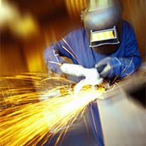 Worker wearing PPE using grinder on metal