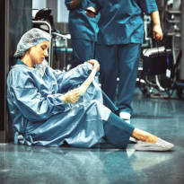 Tired healthcare worker sitting in hallway