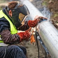 Welder wearing PPE welding on pipeline