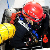 Worker wearing PPE entering confined space with forced air ventilation