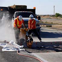 Workers breaking concrete in construction traffice work zone