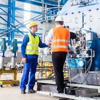 Manager inspecting equipment  with employee