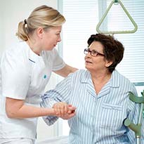 Healthcare worker assisting patient from bed