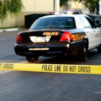 Police car parked at accident scene - caution tape in forground