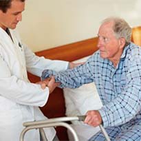 Healthcare worker helping patient out of bed