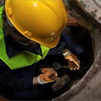 Worker entering confined space on construction site