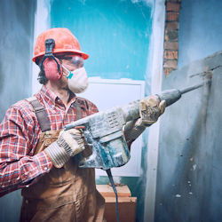 worker demolishing wall exposed to various hazards