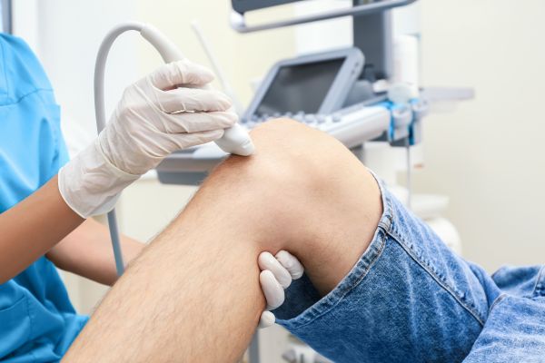 physical therapist using an ultrasound machine on a patient's knee