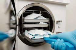 medical professional placing a tray into an autoclave