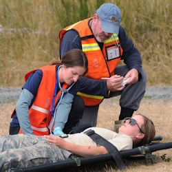 Two workers providing first aid to person laying on stretcher