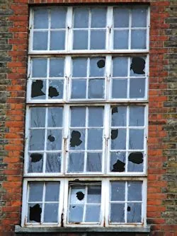 Outdoor view of school windows with multiple panes of broken glass