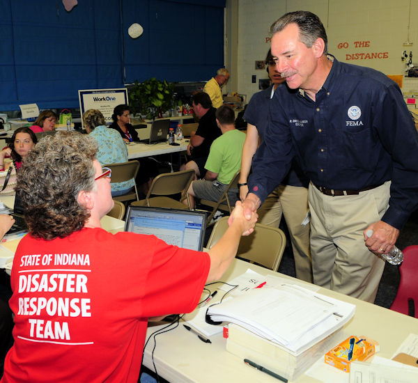 A woman wearing a disaster response team shirt shaking hands with a man.