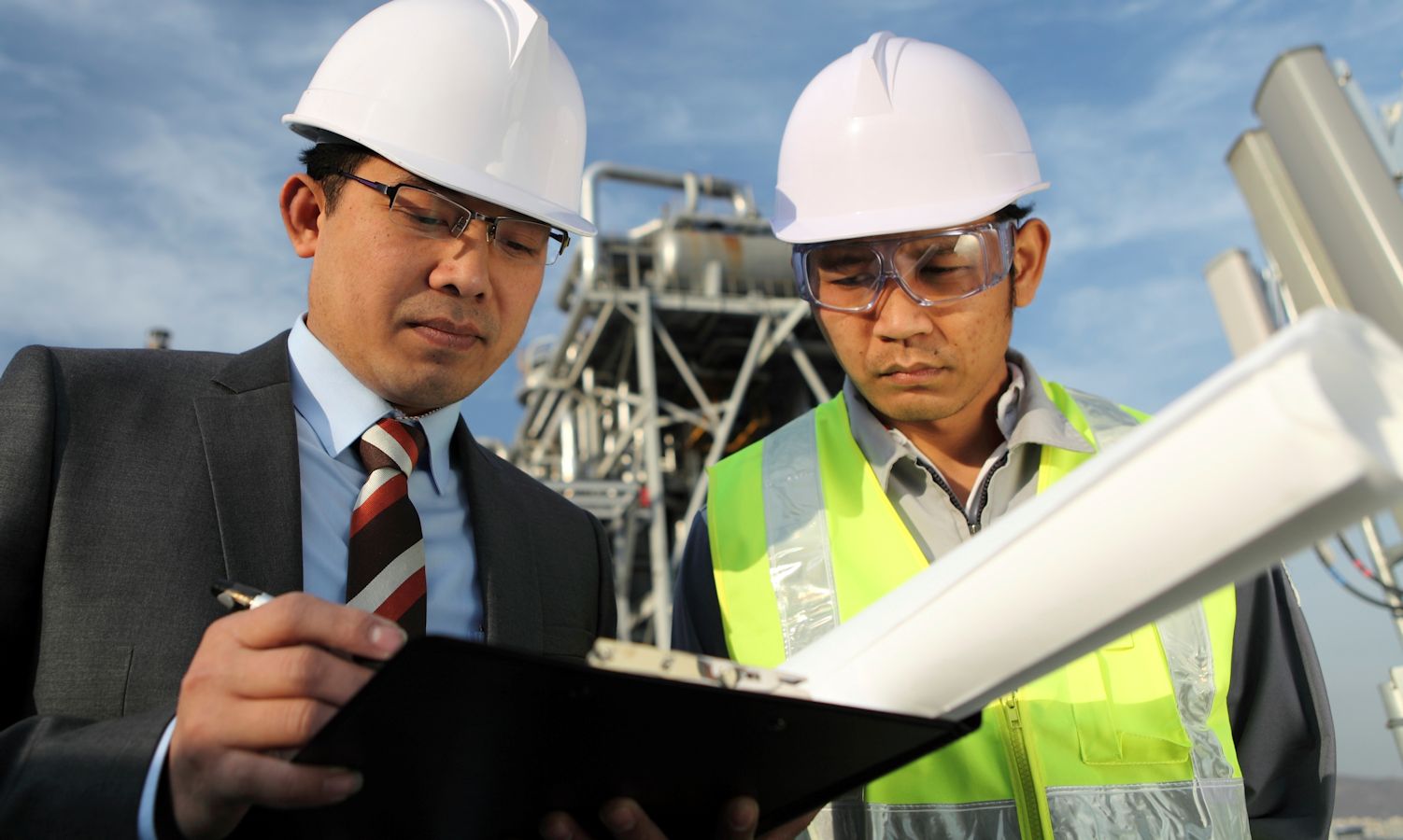 Two workers looking at a clip board.
