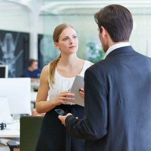 A man and a woman speaking to each other at work.