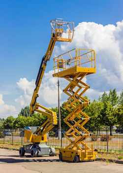 Two pieces of heavy equipment a crane and scissor lift