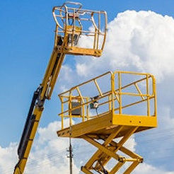 Two pieces of heavy equipment both yellow scissor lift and crane.