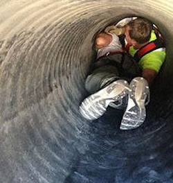 Two men performing confined space rescue training.