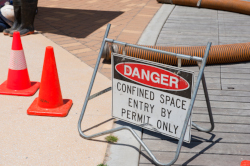 Sign showing DANGER confined space entry with two orange warning cones
