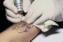 Tattoo Artist working on a clients arm.
