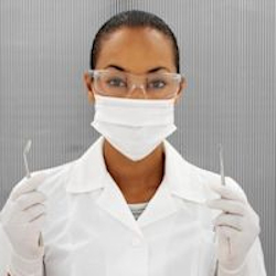 Dental assistant wearing a mask holding a dental tool in each hand.