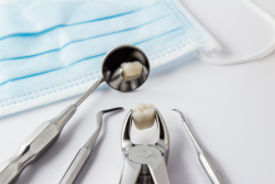 Extracted teeth and the tools to extract them laying on dental tray.