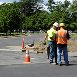 Orange Safety Cones and tubular markers. Three men working in the vicinity