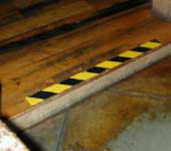 Hazard tape on a bottom step of staircase.