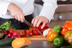 Chef cutting a red pepper with a knife.
