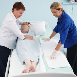 Healthcare providers shifting a patient in bed.