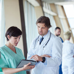 Nurse and doctor speaking in a hallway with other people near them.