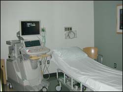 Ultrasound equipment next to a empty bed.