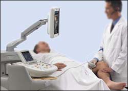 ultrasound tech using an adjustable monitor with equipment while treating patient.