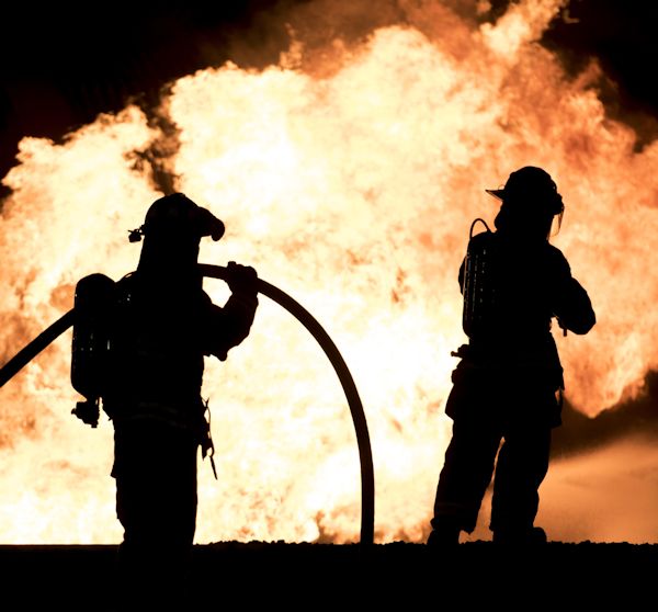 Firefighters fighting a fire at night time.