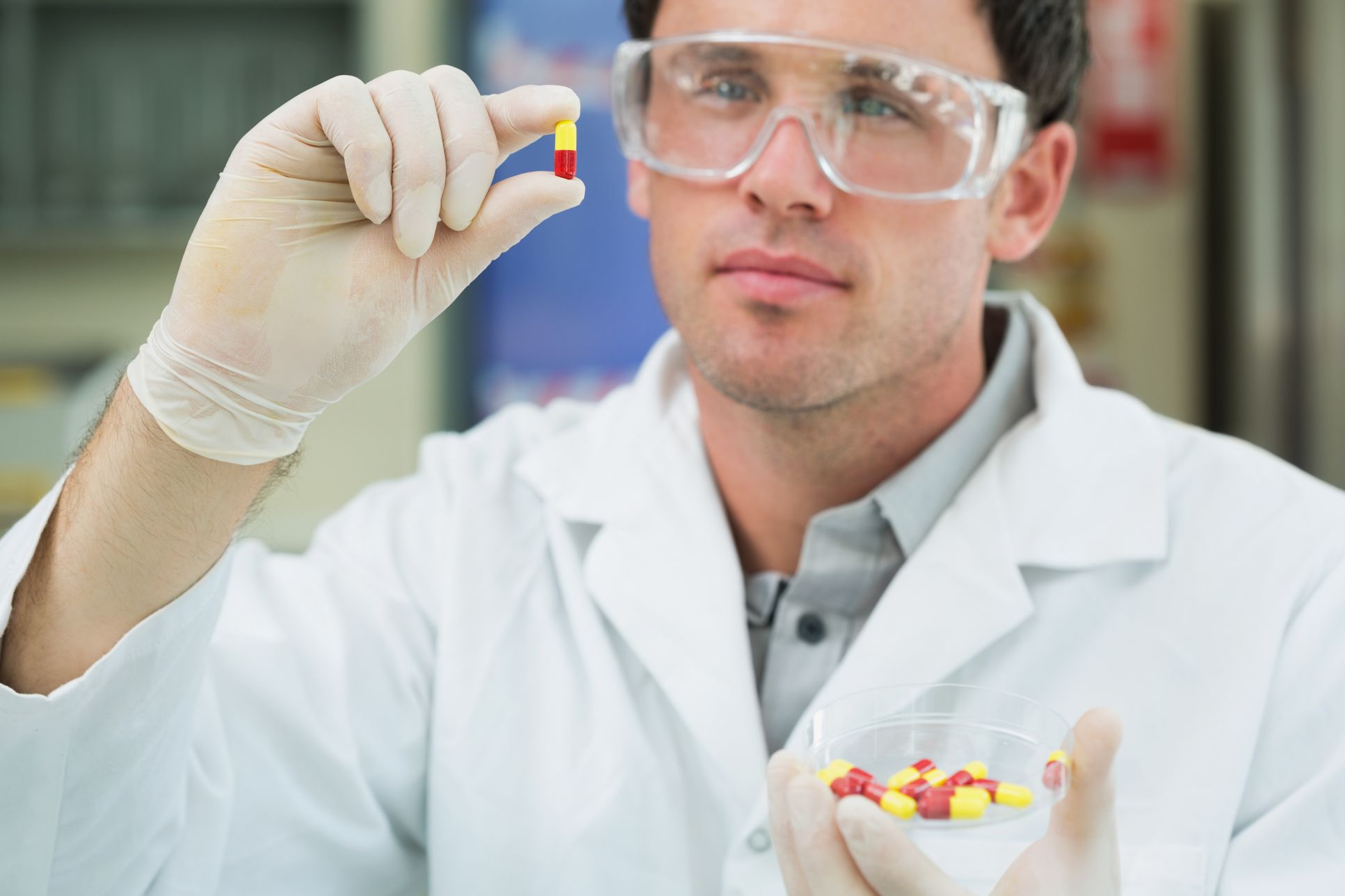 Pharmasist wearing PPE holding a pill.
