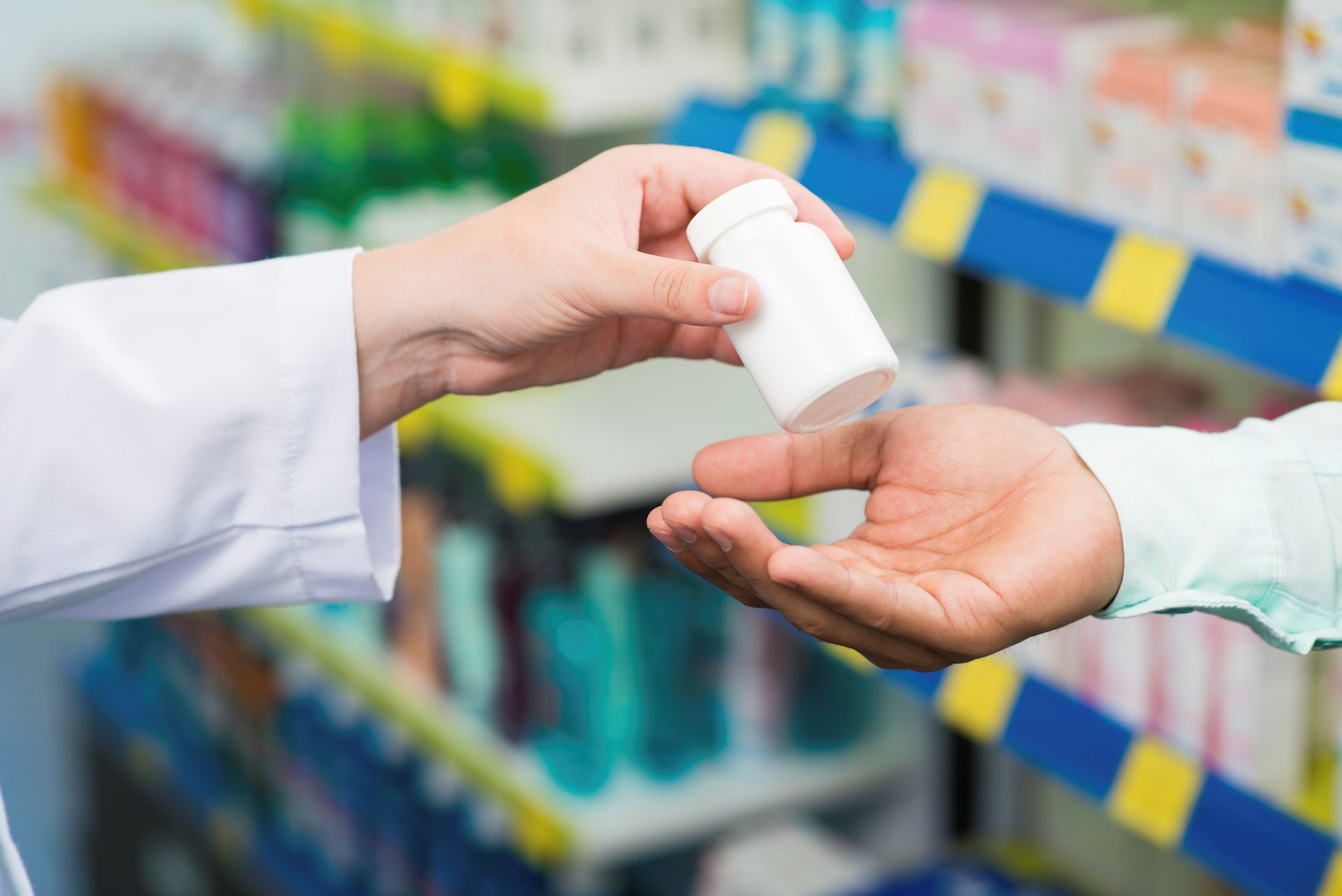 Pharmacist handing prescription medicine to customer.