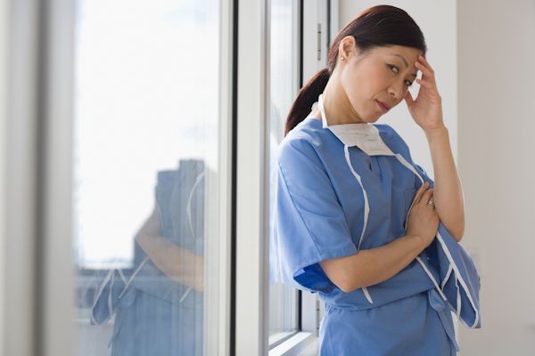 An anesthetist standing in a hallway with a concerned look on her face.