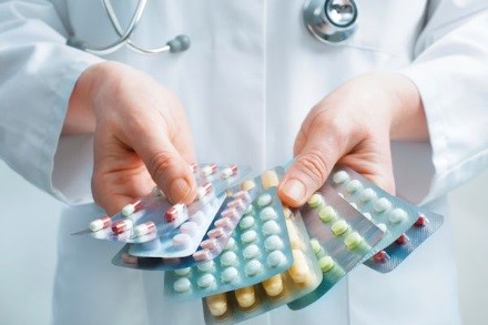 Healthcare provider holding various sealed sleeves of medical capsules.