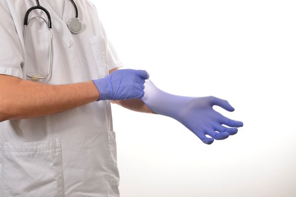Healthcare provider putting on latex gloves.