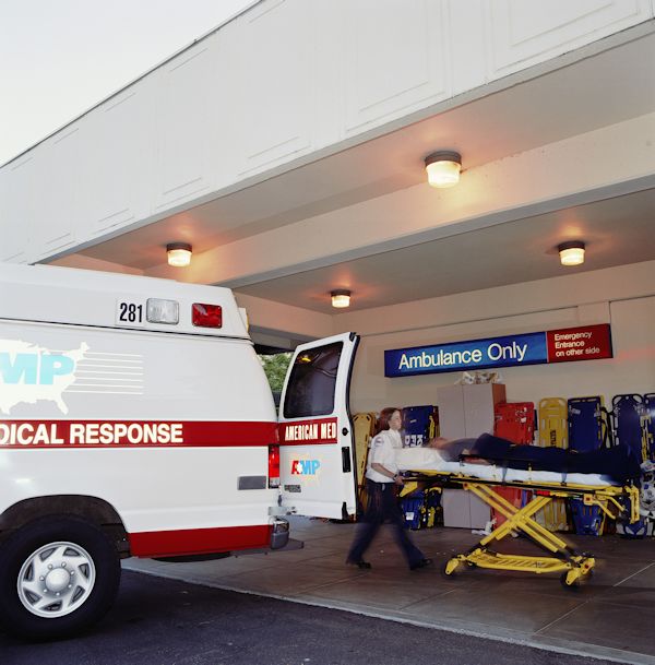 EMTs wheeling a patient on a gurney into a hospital emergency room.