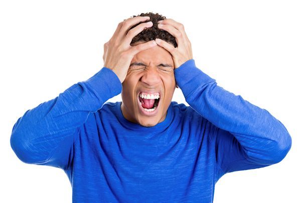 A frustrated man holding his head in his hands and screaming.