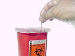 Worker placing a needle in a SHARPS container.