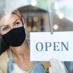 A shop owner posting a store open sign