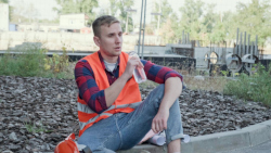 Worker taking a break by sitting on a curb drinking water.