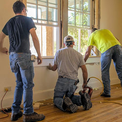 Three workers replacing windows