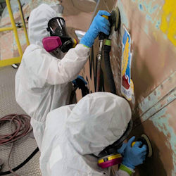 workers removing lead paint from an inside wall