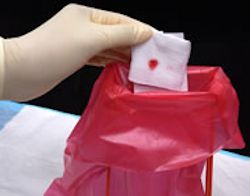 Healthcare provider placing a blood stained tissue in a red bag.