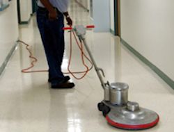 Janitor cleaning the floor of a hospital hallway.