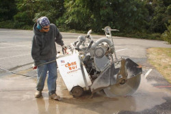 worker walking behind concrete saw