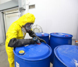 Worker dressed in full PPE filling a barrel