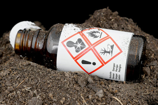 Opened bottle of clearly marked hazardous poison laying on ground